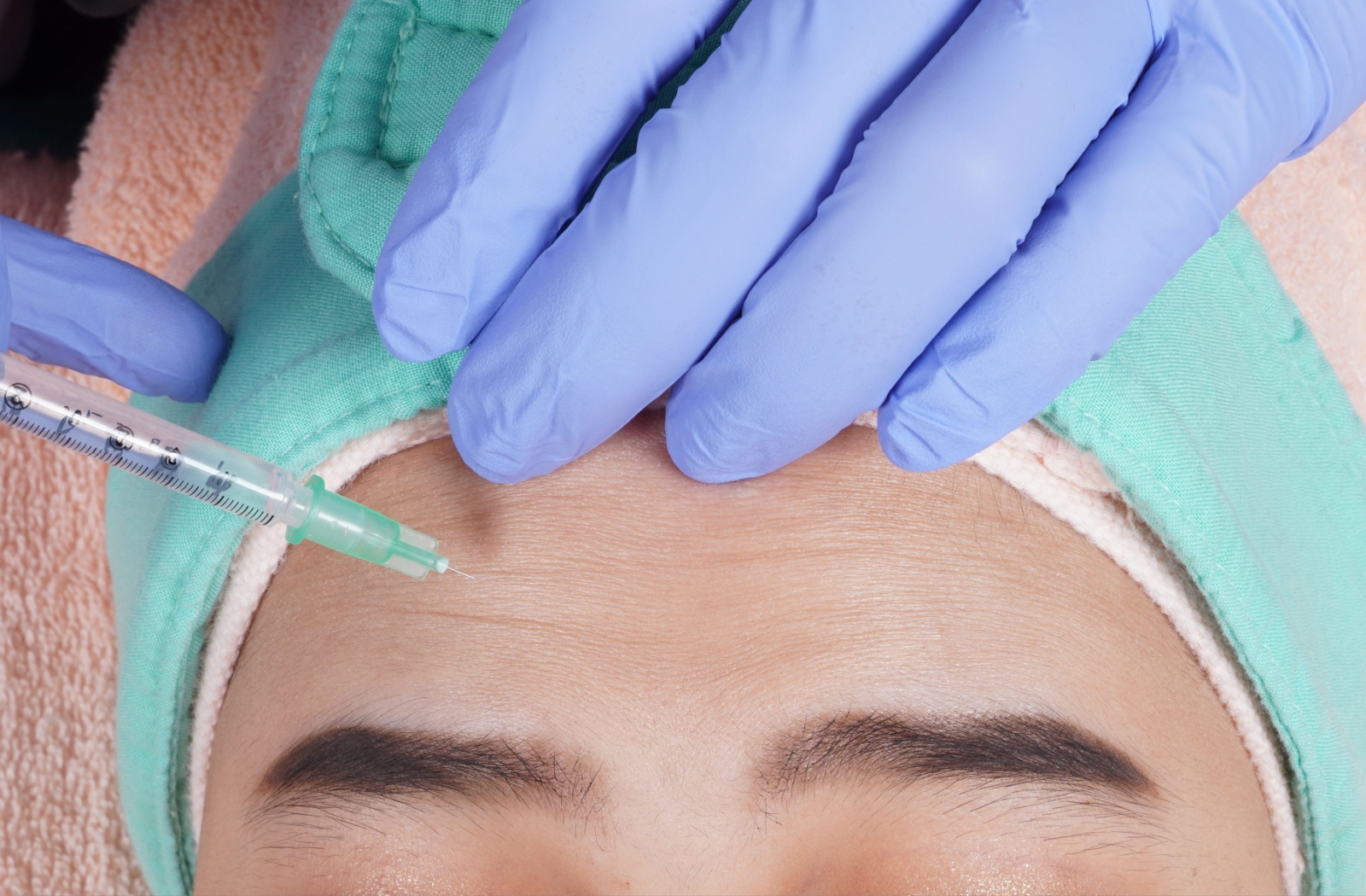 A close up a woman's forehead being injected with botox