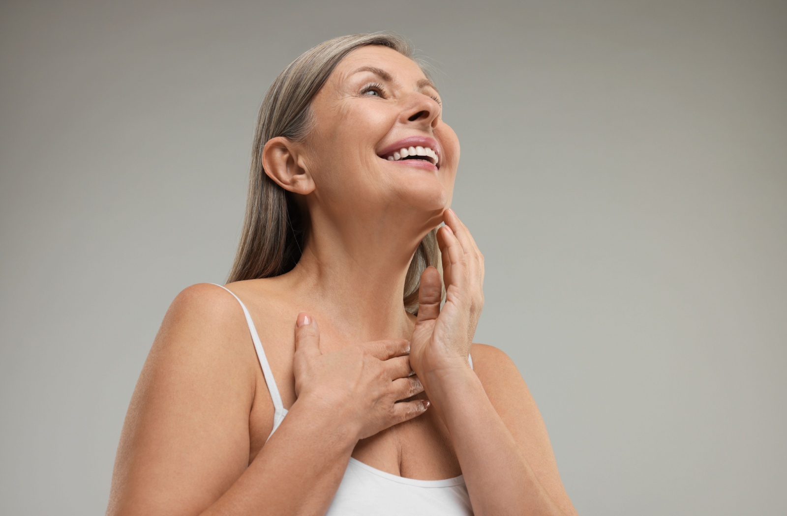 A person smiling and looking up to show off smooth, tight neck skin