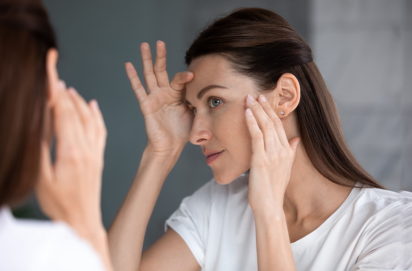 A person looking in the mirror, examining their skin after a CO2 laser procedure.