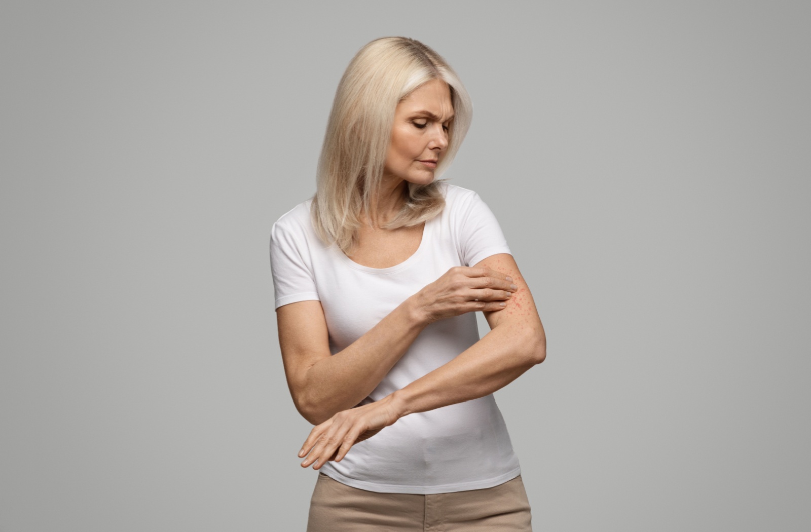 Someone frowns as they examine their arm for skin lesions.